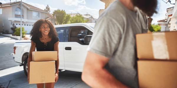 a couple carrying boxes as they do their own move